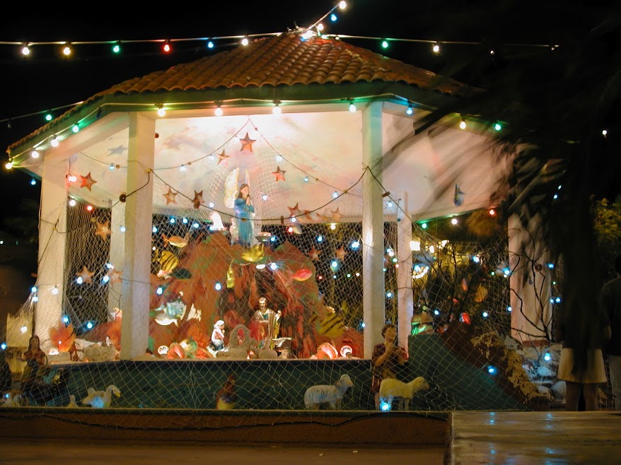 The gazebo at the centre of the Isla Mujeres plaza decorated in an underwater-themed nativity scene. The virgin mary stands at the centre, her hands in prayer. Fishing nets filled with starfish, tropical fish, and multi-coloured Christmas lights surround the gazebo.