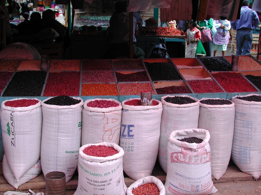 Dozens of varieties of dried beans in many colours arrayed for sale in bins and large sacks for sale at the market